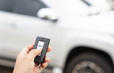 Fototapeta premium Closeup woman hand holding car key remote with car background