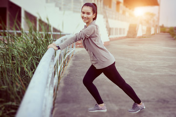 Health, sport and workout concept - Young Asian woman warm up body before jogging and workout daily. Female runner does stretching body to warm up before exercise.