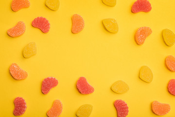 top view of delicious lemon, grapefruit and orange jellies on yellow background with copy space