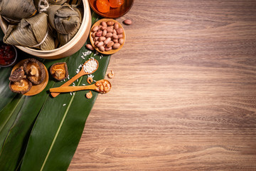 Zongzi, steamed rice dumplings on wooden table bamboo leaves, food in dragon boat festival duanwu concept, close up, copy space, top view, flat lay