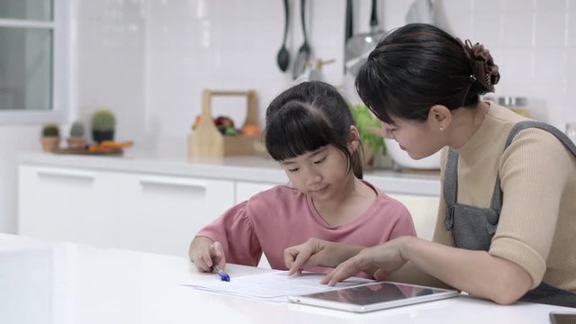 Asian Mother Teaches Homework To Daughter At Home. Asian Family Study And Learning With Tablet Together. Concept Of Education, Technology, Happy Family And Activity Holiday.