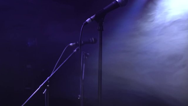 detailed shot of dynamic microphone in an empty studio with neon blue and red lights flashing.  the fog slowly rolls on the set before the band performance begins to play some awesome music 