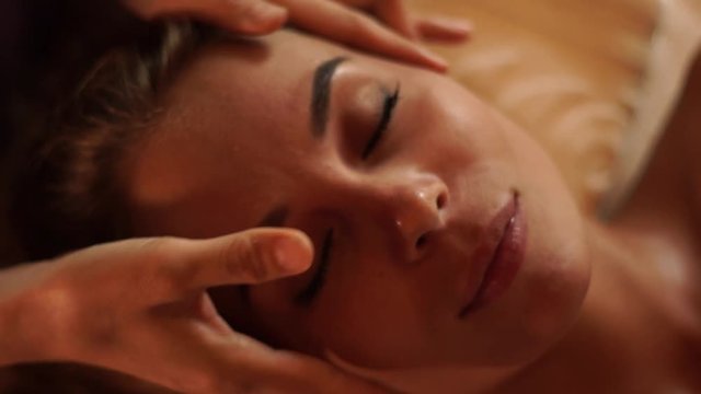 Face young woman receiving skin massage in beauty spa salon. Close up portrait woman getting face massage in cosmetic spa studio. Skin care, beauty concept.