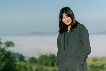 Asian woman Put on a smiling winter coat In the tourist area behind the fog and mountains with a smiling expression of happiness