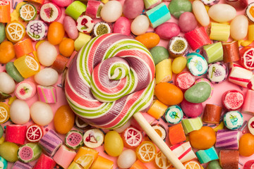 Fototapeta na wymiar top view of bright delicious multicolored caramel candies and swirl round lollipop on wooden stick