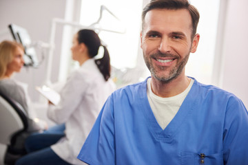 Obraz premium Front view of smiling male dentist in dentist's clinic