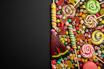 top view of delicious multicolored candies on black background with copy space