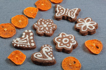 Gingerbread cookies decorated with a pattern of white glaze. On a background of gray fabric. Decorated with decorative elements of dried fruit