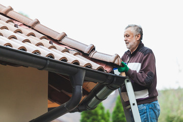 man repairs tiled roof of  house close up