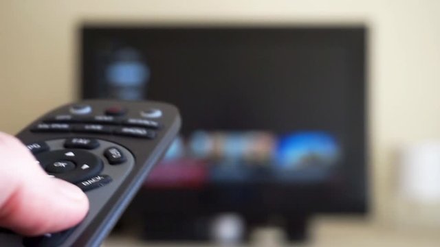 Close up shot of a male left hand holding the TV remote control and changing television channels