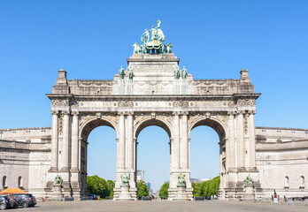 Fototapeta na wymiar Front view of the eastern side of the arcade du Cinquantenaire, the triumphal arch erected in 1905 by king Leopold II in the Cinquantenaire park in Brussels, Belgium, against blue sky.