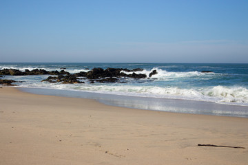 Waves crashing on rocks on Atlantic Ocean beach. Scenic seascape. Beautiful surf at seaside. Splashing waves with foam. Travel and vacation on shore. Rocky coastline. Nature power.