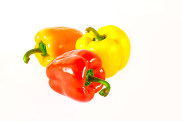 Juicy red, orange and yellow peppers with a green tail lies on a white background