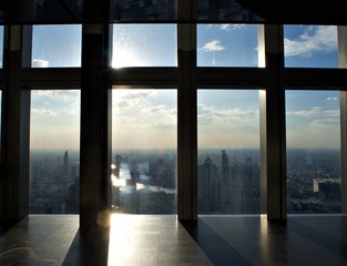 The evening sun with glass wall and the shadow, cloud and the landscape of Bangkok at MahaNakhon building