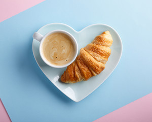 Cup of coffee and freshly baked croissants on blue background. Top view. Copy space.