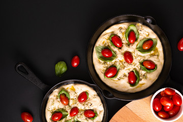 Food concept rising dough for Homemade organic Focaccia in skillet iron pan on black background with copy space