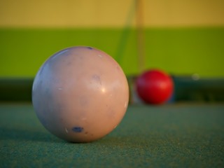 Focus shot on the white ball with blur red billiard ball at background on the pool