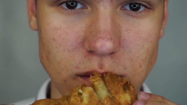 Boy is eating the big crispy chicken feet. Concept street food or fast food