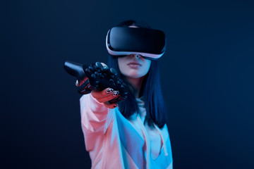 selective focus of young woman holding joystick while using virtual reality headset on blue