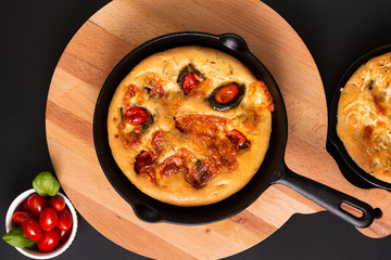 Food concept fresh baked Homemade organic Focaccia in skillet iron pan on black background with copy space