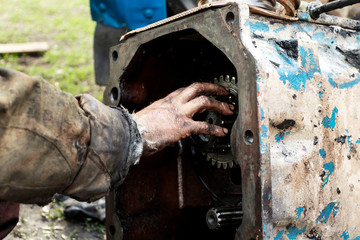 Man repairs engine of tractor, agricultural machinery. Bearing, gears, close-up.