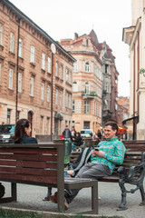 Fototapeta premium laughing talking man with woman sitting on bench drinking coffee surfing in internet. urban lifestyle