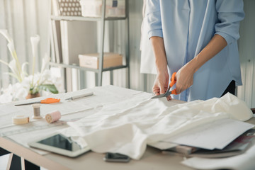 Young female fashion designer working on her designs in the studio. Fashion designer drawing sketches for new collection. Beautiful fashion woman designer drawing in studio .