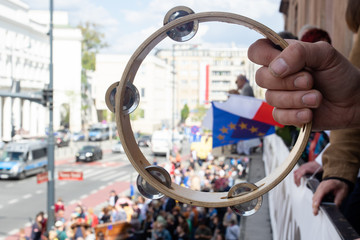 Right hand holding a tambourine over the street - obrazy, fototapety, plakaty
