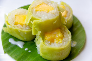 Mango sticky rice with coconut milk roll on banana leaf