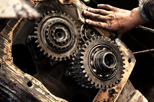 Man repairs engine of tractor, agricultural machinery. Bearing, gears, close-up.