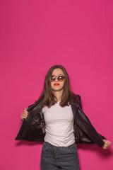 Fashioned girl in leather jacket in dark glasses in pink and blue  neon lights background. 