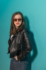 Fashioned girl in leather jacket in dark glasses in pink and blue  neon lights background. 