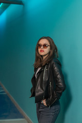 Fashioned girl in leather jacket in dark glasses in pink and blue  neon lights background. 