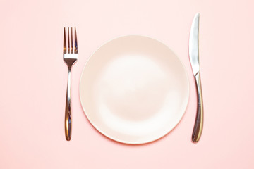 Pink empty plate with fork and knife on a pink tablecloth