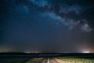 Blue Night Starry Sky Above Country Asphalt Road In Countryside And Green Field. Night View Of...