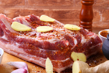Raw fresh meat, uncooked lamb or beef ribs with pepper, garlic, salt and spices on dark stone background, Ready for cooking. copy space.
