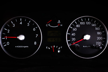 Car dashboard gauges on black background.