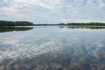 Sunrise over the forest lake. Reflection of the sky in the lake. Summer