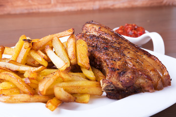 Grilled pork ribs with potato free and sauce on white plate.