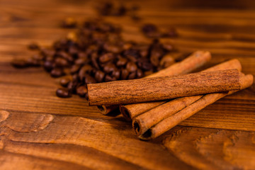 Pile of the coffee beans and cinnamon sticks on wooden table