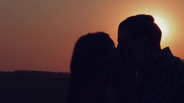 Young lovers kissing at sunset