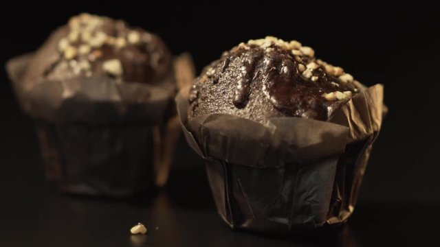 Chocolate muffin falling into frame in black background. Two chocolate muffin composition in slow motion
