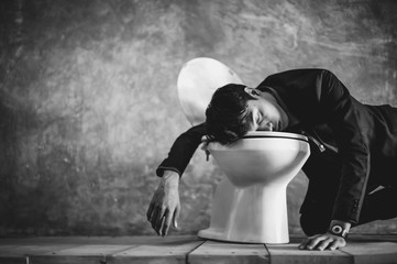 A young businessman is sleeping in the bathroom. Because of fatigue from drinking Caused by...