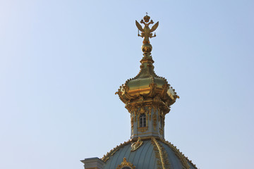 Fototapeta na wymiar Double-headed eagle symbol of Russian Federation on top of golden dome. Gilded cupola on historical building roof close up view o