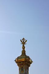 Fototapeta na wymiar Golden dome with two headed eagle - symbol of russian empire on top. Gilded cupola close up view isolated on blue sky background 