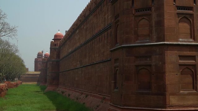 Corner view of exterior wall at the Red Fort with lush green grass. Handheld.