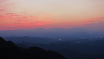 Fototapeta premium Silhouette of mountain range with beautiful layers of it's peak and orange sunset background.