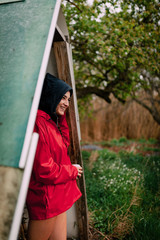 Smiling girl wearing red raincoat takes shelter from the rain