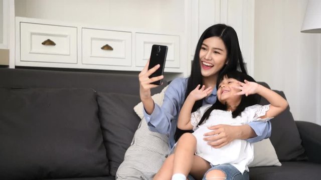 Family concept. Mom is inviting her daughter to take pictures in the living room.