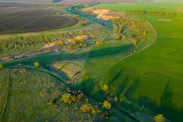 Fototapeta na wymiar Spring fields, meadows, ravines at sunset from the quadrocopter